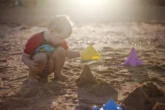 Der kleine Junge konzentriert sich auf den Bau von Sandburgen