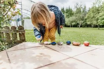 Maza meitene spēlējas ar akmeņiem