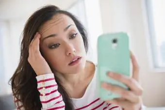 Sieviete savā tālrunī skatās sociālos tīklus