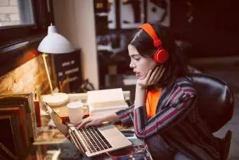 Jonge vrouw die laptop gebruikt terwijl ze naar muziek luistert