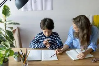 Tutor legt de jongen uit via een boek op tafel thuis