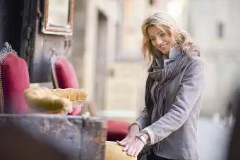 Perakendeci antika dükkanının dışındaki sandalyeye bakarken kadın müşteri işaret ediyor