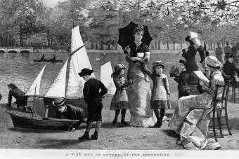 Des petits garçons jouent avec des bateaux et une famille se promène près de la Serpentine lors d'une journée ensoleillée d'automne