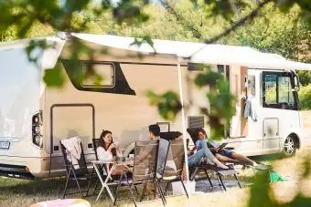 Družina se med poletnimi počitnicami sprošča na stolih pred avtodomom v kampu