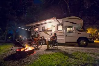 Couple et petite fille assis devant un feu de camp la nuit