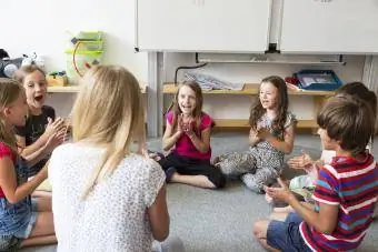 Enseignant et élèves assis par terre dans leur classe