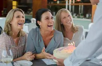 Mężczyzna wręczający kobietom tort urodzinowy