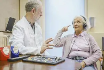 Patient senior portant des écouteurs et parlant à un audiologiste