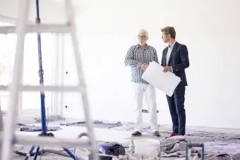 Hombre de traje y hombre mayor hablando en una habitación en construcción