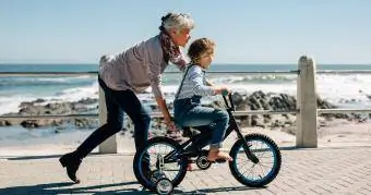 baka uči unuku voziti bicikl na plaži