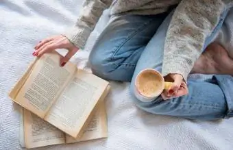 Donna a letto con caffè e libro