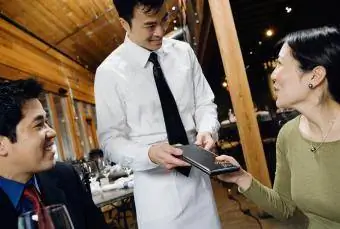 Femeie asiatică care plătește factura la restaurant