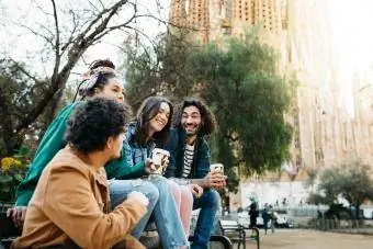 Hymyilevät ystävät ottavat selfietä istuessaan penkillä