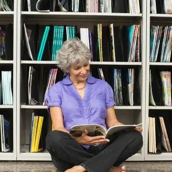 Nainen lukee lehteä kirjastossa