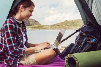 Ženska uporablja prenosni računalnik v šotoru v gori