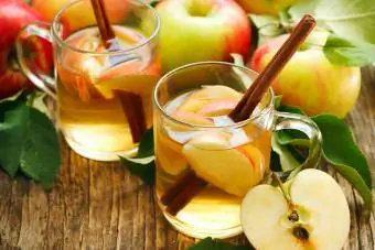 Twee Apple Pie Toddy met appels op 'n houttafel