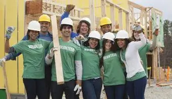 Доброволци, аплодиращи успешното изграждане на дома