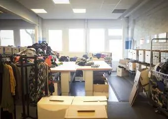Îmbrăcăminte și cutii pentru donații într-un magazin de second hand puternic luminat
