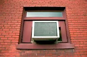Unidad de aire acondicionado de ventana en casa de ladrillo rojo.