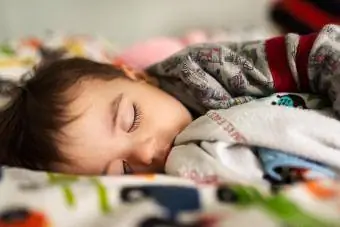 Niño pequeño durmiendo en una cama intentando recuperarse del frío