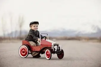 Un ragazzo è fuori a fare un giro con la sua macchina a pedali.