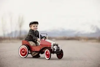 En ung guttesjåfør er ute og kjører i pedalbilen sin.