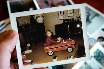 La mano tiene la fotografia d'epoca del ragazzo in macchina a pedali