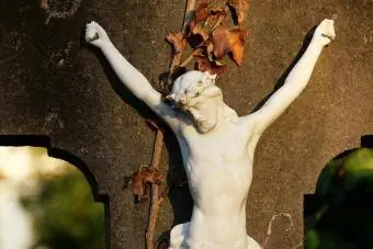 Crucifixo branco abandonado numa pedra cinzenta sob a luz solar