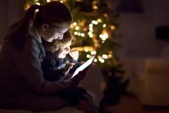 Mor med sønnen ser på et digit alt nettbrett i mørket