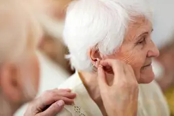 Médecin appliquant une aide auditive à l'oreille d'une femme âgée