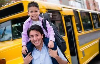 Tėvas nuveža sūnų į mokyklinį autobusą